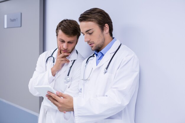 Doctors using digital tablet in corridor