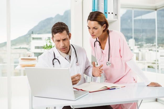 Doctors using laptop at medical office