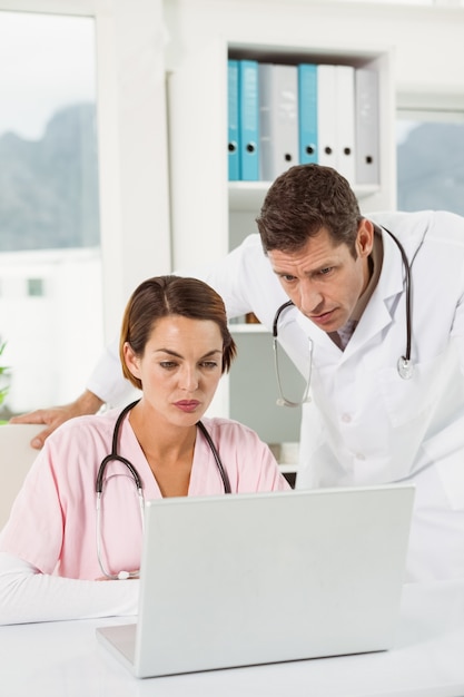 Doctors using laptop together at medical office