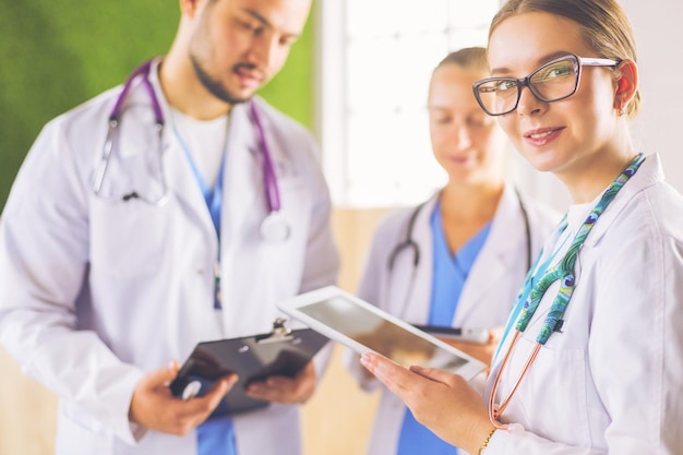 Doctors using a tablet in hospital standing in office