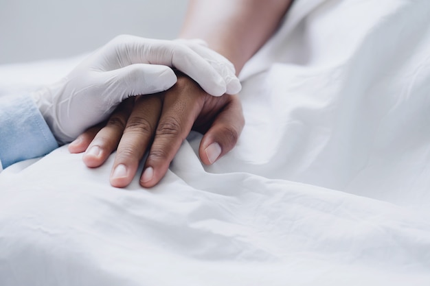 Doctors wear medical gloves holding touching hands man patient with love, care, helping, encourage and empathy at nursing hospital ward.healthy strong medical concept