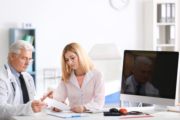 Doctors working at table with computer in clinic