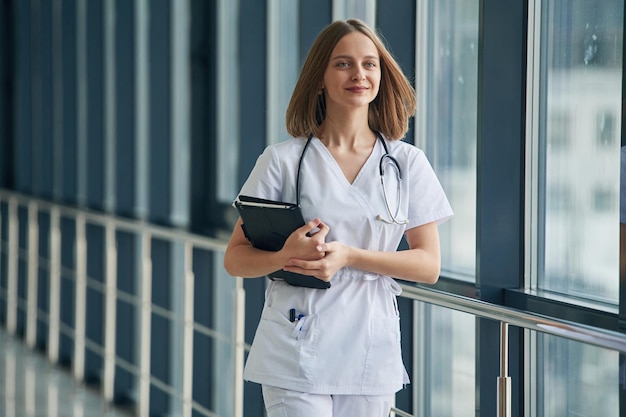 Document in hands Female doctor in white coat is in the hall
