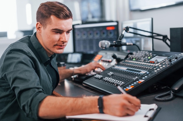 Document with scenario Young man is indoors in the radio studio is busy by broadcast