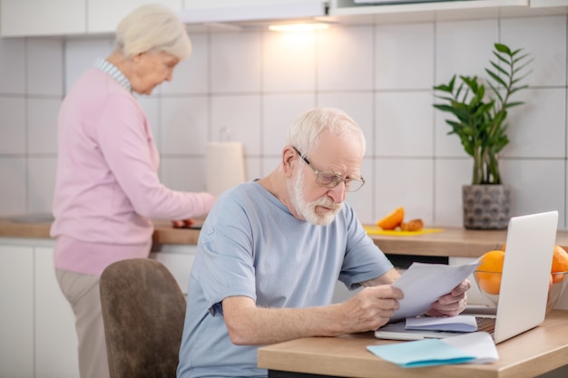 Documenten. Bebaarde senior man iets lezen en serieus kijken