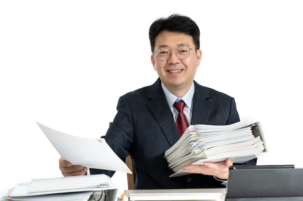 アジアの中年男性ビジネスマンと積み重ねられた文書やレポート。