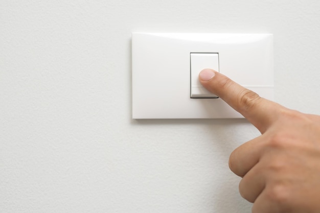 Doe het licht uit close-up vinger man hand sluit de aan / uit-schakelaar met muur thuis om energie te besparen en de opwarming van de aarde te verminderen