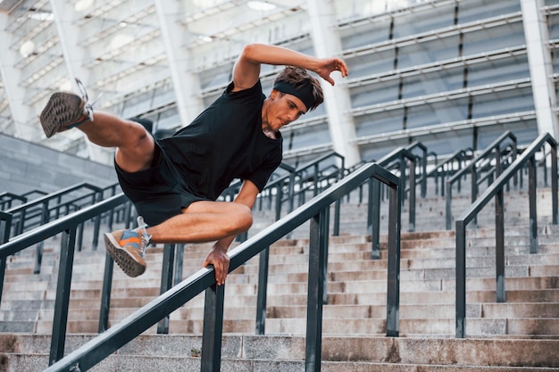 Паркур Молодой человек в спортивной одежде тренируется на открытом воздухе в дневное время