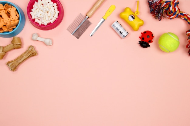 Dog accessories, food and toy on pink background. Flat lay. Top view.