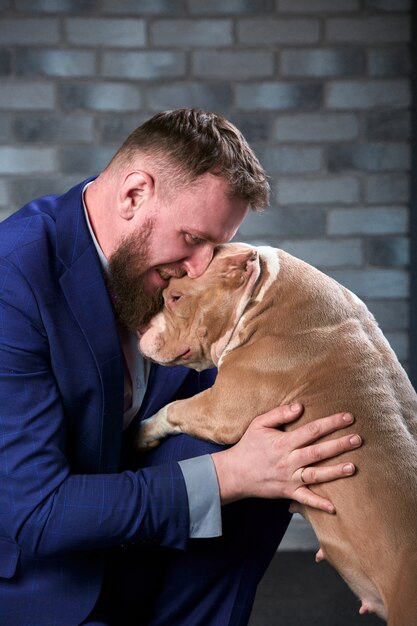 Dog bulli en haar baasje, haar liefhebbende meester die de hond in haar armen houdt, knuffels en kusjes. De hond voelt zich goed in de handen van de eigenaar