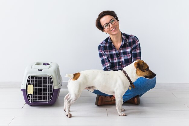 犬のキャリーバッグとペットの飼い主のコンセプト-格子縞のシャツを着た魅力的な陽気な女性がお気に入りを保持します