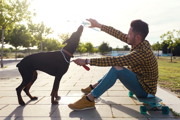 Photo dog drinking water from the plastic bottle in the park.