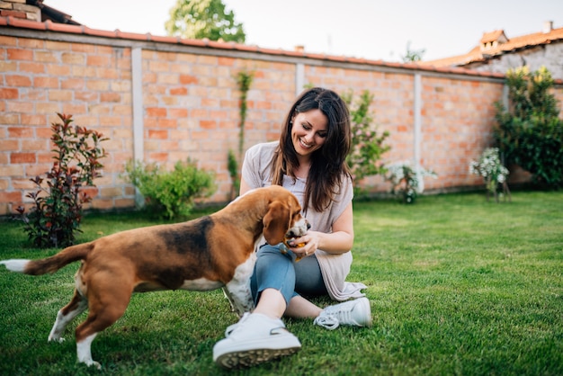 屋外の美しい若い女性によって彼に与えられたおいしい食べ物を食べる犬。