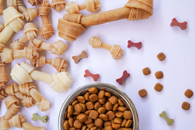 dog food in a bowl and knotted bone on white background