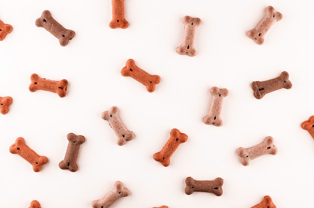Photo dog food pattern made with dry snacks in shape of bones. funny cute flat lay texture. home pets, animals feeding. special diet, training supply.