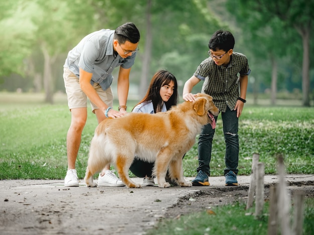 犬のゴールデンレトリーバー公園でアジアの家族と遊ぶ