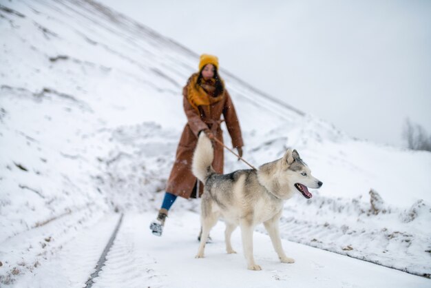 冬の雪山の犬のハスキーと女性