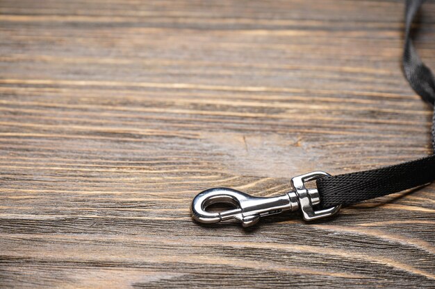 Dog leash with carabiner on a wooden background, space for text. Close-up.