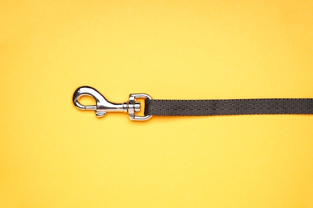 Dog leash with carabiner on a yellow background, close-up.