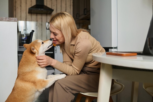 Photo dog licking face of young cheerful woman