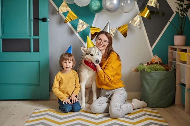 犬のペットの誕生日の家族の母と子は、お誕生日おめでとう犬を抱きしめる