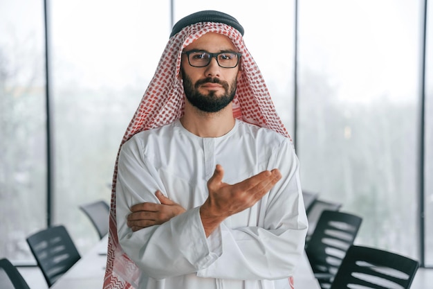 Doing gestures by hands Successful Muslim businessman in traditional outfit in his office