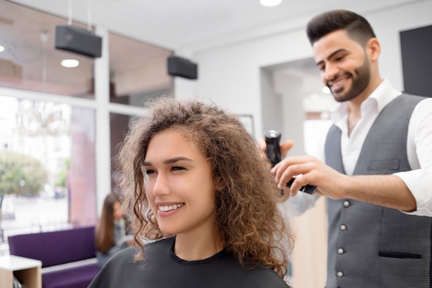 Doing hairdress for smiling curly female client.