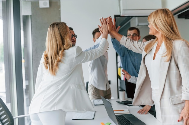 doing high five successful agreement group of professional business people is in the office