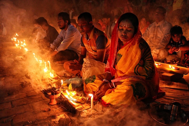 バロディ・ロクナス・ブラハマチャリ・アシュラムで 燃えるキャンドルとダイア・オイル・ランプの前で祈りをしています