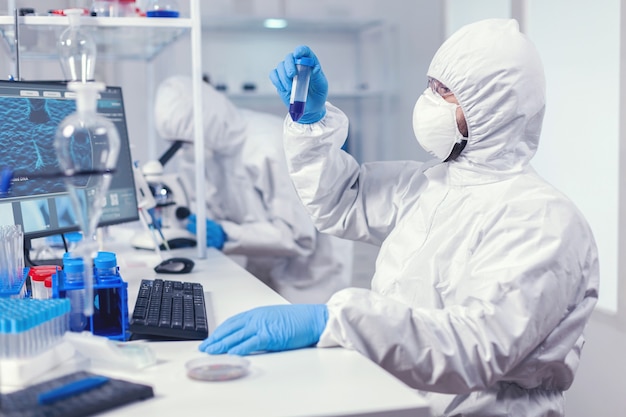 Doing research to find a vaccine for coronavirus dressed in ppe suit. Scientist in laboratory wearing coverall doing research and analyzing substance during global pandemic with covid19.