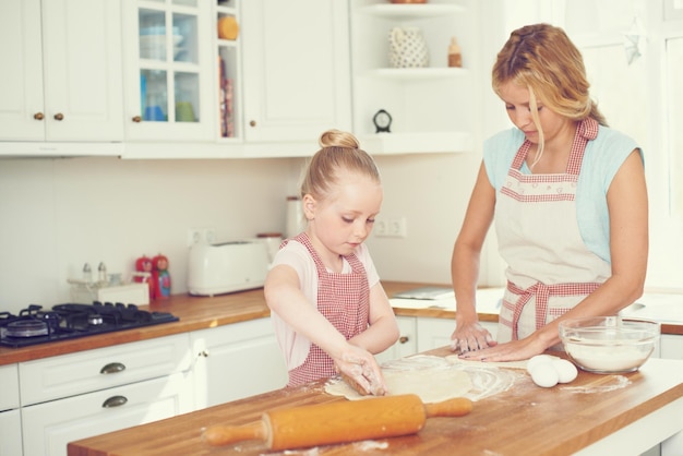 Doing some bonding over baking Cute little girl baking in the kitchen with her mom