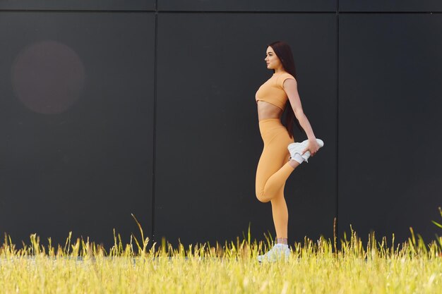 Делать растяжки Молодая женщина в спортивной одежде занимается фитнесом на открытом воздухе