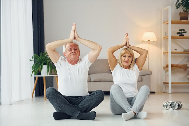 Doing yoga senior man and woman is together at home