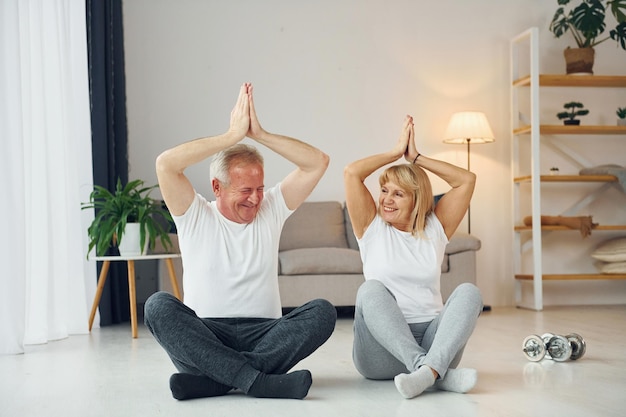 Doing yoga senior man and woman is together at home