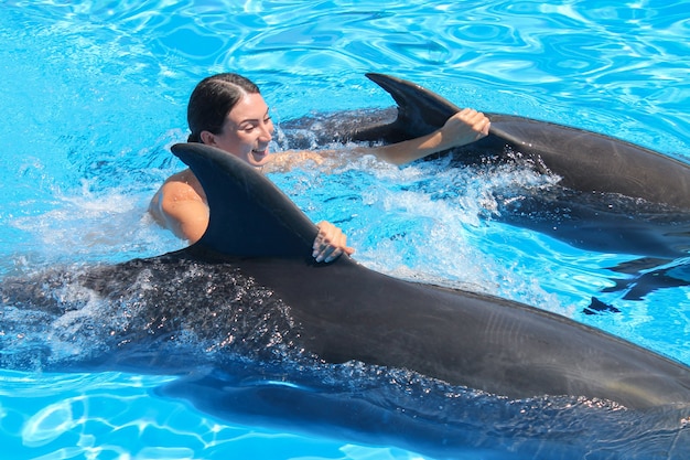 Doiphins rijden gelukkige jonge vrouw in blauw water.