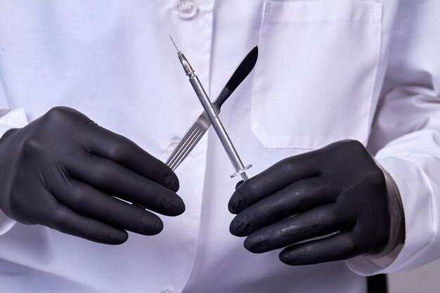 Dokter-chirurg heeft een scalpel met spuit chirurgisch concept instrument