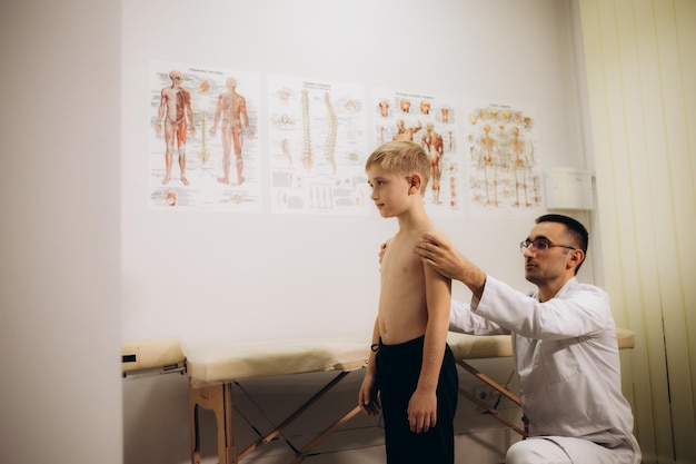 Dokter controleert de houding van een kleine jongen in de kliniek.