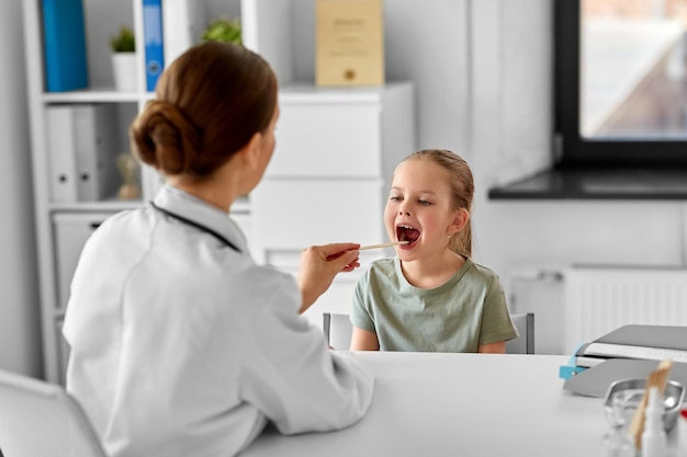 Dokter controleert de keel van een meisje in de kliniek.