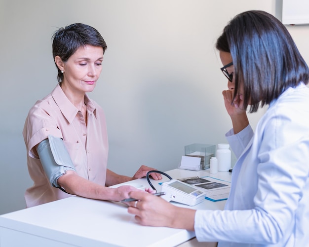 Dokter die de bloeddruk van de patiënt meet met een bloeddrukmeter op het kantoor van de kliniek