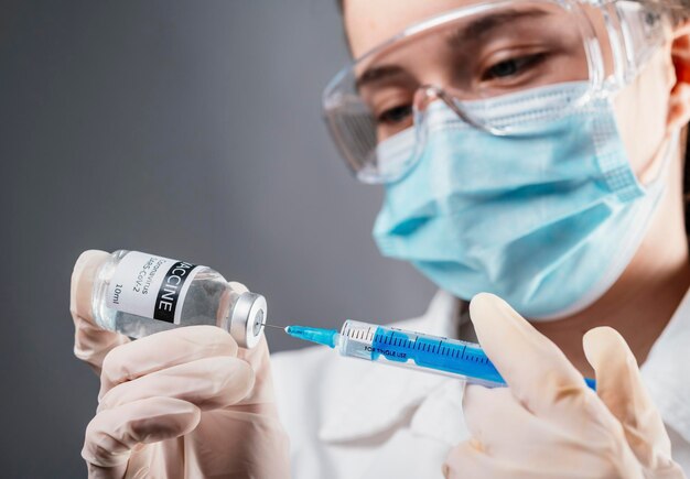 Foto dokter die een injectiespuit vasthoudt met een flacon met een enkele fles covid19-vaccin voor kinderen of volwassenen concept strijd tegen virus close-up detail medisch concept vaccinatie behandeling met onderhuidse injectie