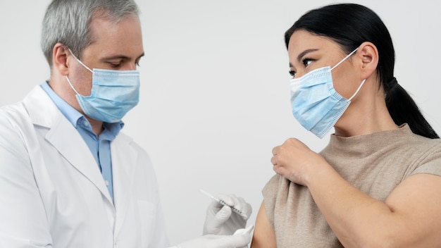 Foto dokter die vaccin toedient aan vrouwelijke patiënt