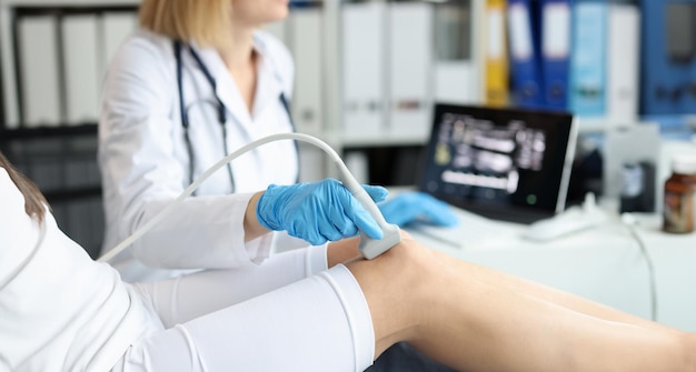 Dokter doet een echografie van het kniegewricht van de patiënt in de kliniek