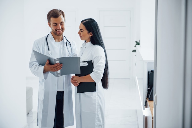 Dokter en brunette verpleegster staan in het ziekenhuis en praten op het werk.