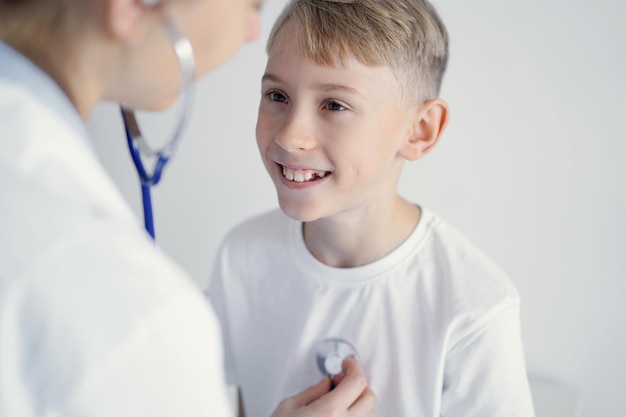 Dokter en gelukkig lachend kind jongenspatiënt bij gebruikelijke medische inspectie in kliniek. Geneeskunde, gezondheidszorgconcepten
