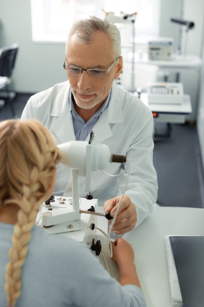 Foto dokter en meisje. blondharig meisje met twee vlechten op bezoek bij oogarts voelt zich goed