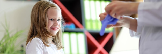 Dokter en meisje deden medische handschoenen aan in het kinderartsconcept van kliniekkinderen