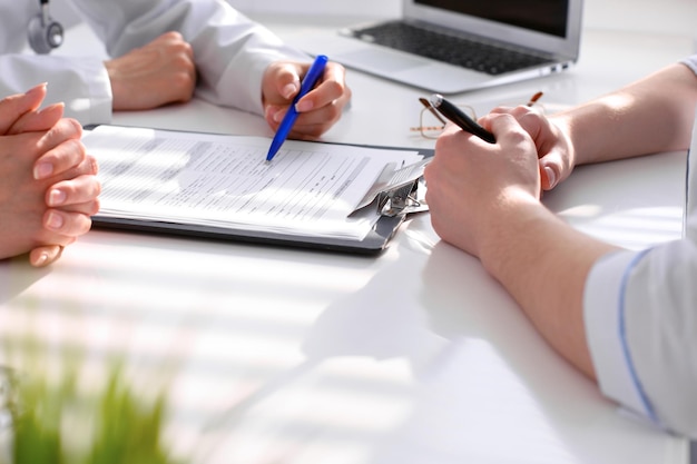 Dokter en patiënt bespreken iets gewoon handen aan tafel