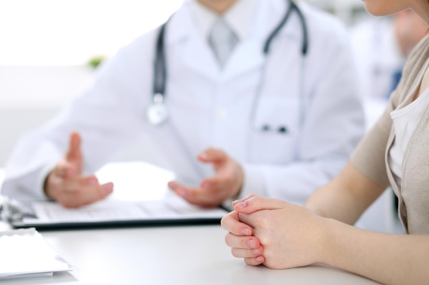 Dokter en patiënt bespreken iets gewoon handen aan tafel