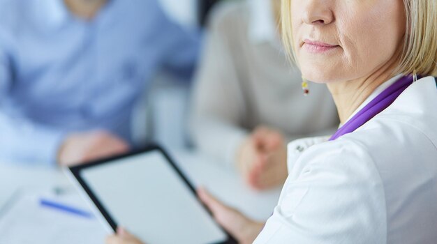 Foto dokter en patiënt zitten aan de balie arts wijzend naar tablet pc