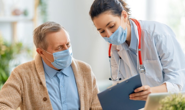 Dokter en senior man met gezichtsmaskers en ziektebescherming thuisquarantaine COVID2019